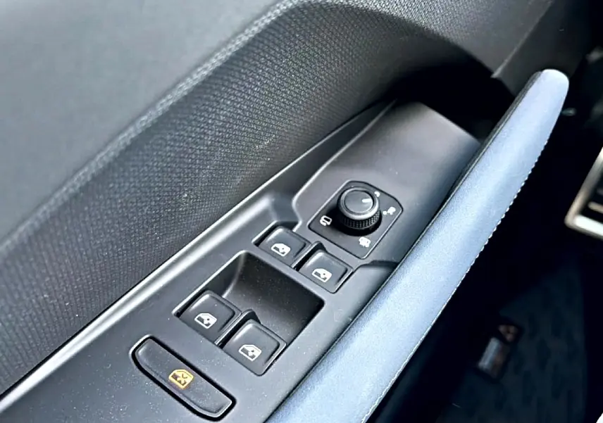 Gros plan sur la commande des vitres et rétroviseurs côté conducteur avec accoudoir bleu dans une CUPRA Terramar 2026.