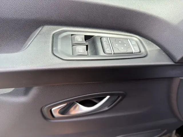 Gros plan sur la commande des vitres et la poignée de porte intérieure côté conducteur du Nissan Primastar noir 2025.