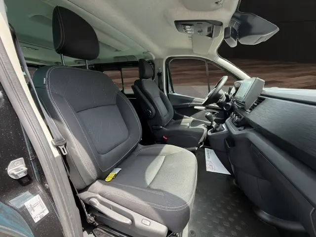 Intérieur avant du Nissan Primastar noir 2025, vue côté conducteur montrant sièges tissu et tableau de bord avec écran tactile.