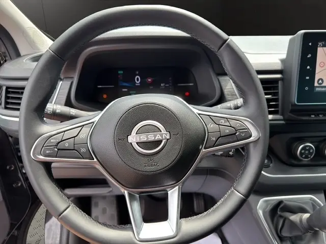 Vue rapprochée du volant noir en cuir synthétique du Nissan Primastar 2025 avec commandes multifonctions et tableau de bord digital.