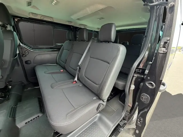 Vue intérieure côté droit du Nissan Primastar noir, montrant les sièges passagers arrière et la porte latérale ouverte.