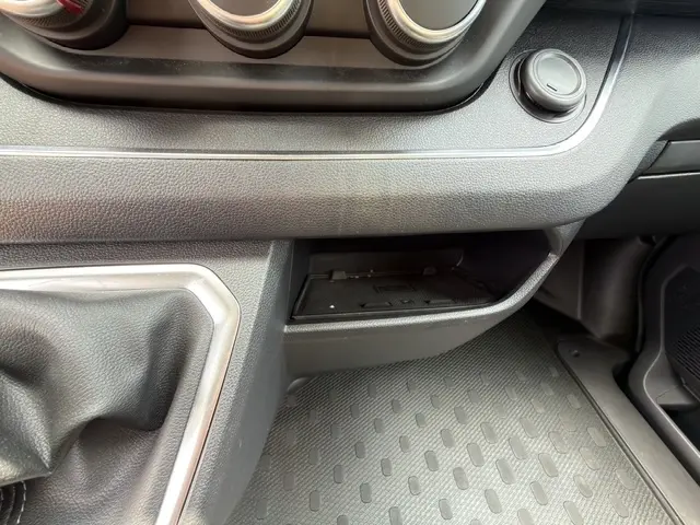 Détail de la console centrale noire du Nissan Primastar 2025, avec zone de recharge par induction et commande manuelle.