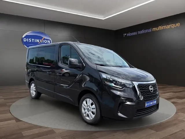 Nissan Primastar noir en 3/4 avant droit, avec calandre chromée et feux LED, sur plateau intérieur showroom.
