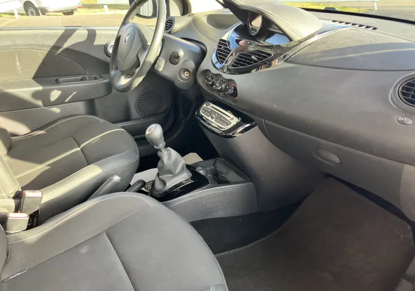 Intérieur noir de Renault Twingo II 2011 vu côté conducteur, avec volant, levier de vitesses manuel et tableau de bord épuré.