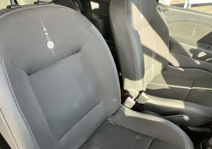 Vue rapprochée des sièges avant noirs de la Renault Twingo II 2011, montrant les détails de la sellerie et les ceintures de sécurité.