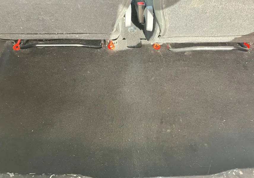 Vue du coffre arrière du Renault Twingo II noir de 2011, montrant la moquette et la base des sièges arrière.