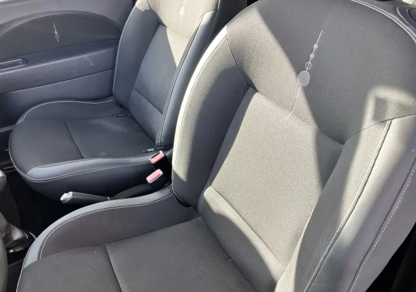 Gros plan sur les sièges avant noirs de la Renault Twingo II 75CH ESS de 2011, avec coutures blanches et motifs discrets.