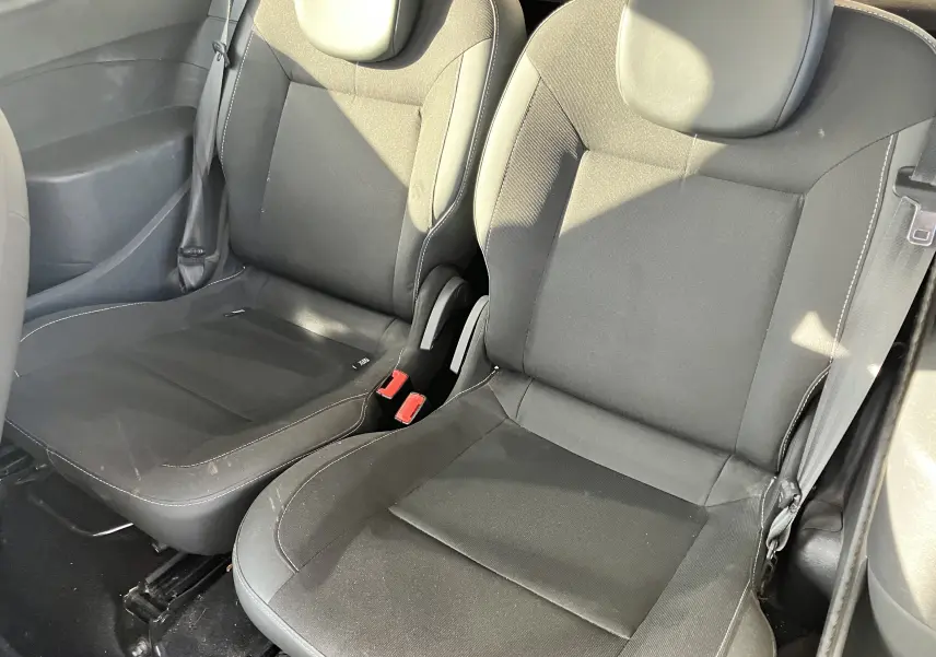 Vue rapprochée des sièges avant noirs de la Renault Twingo II 75CH ESS de 2011, montrant les ceintures et appuie-têtes.