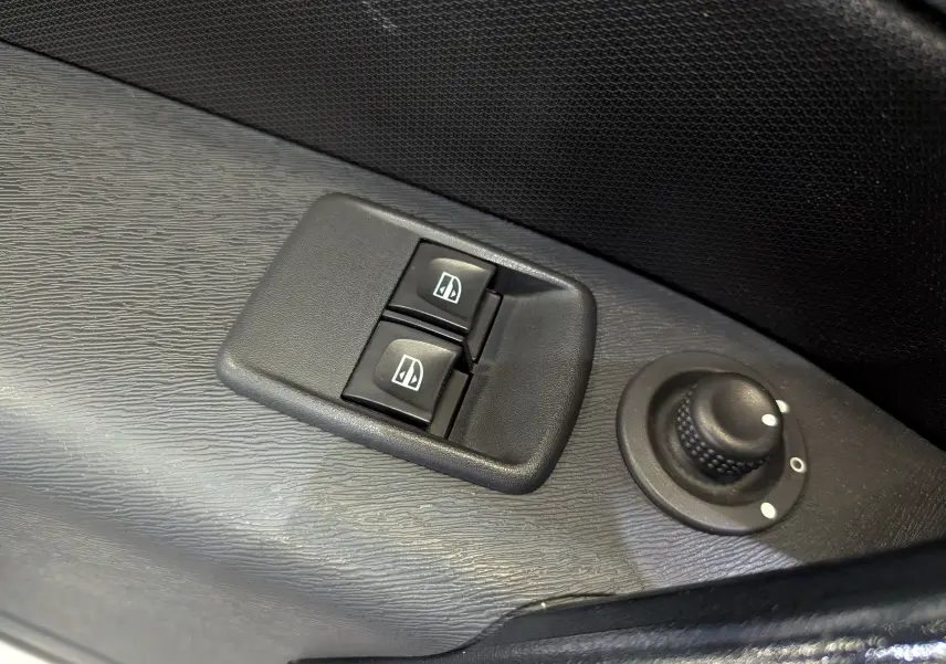 Gros plan sur les commandes des vitres électriques et le réglage des rétroviseurs côté conducteur du Renault Kangoo Express blanc.