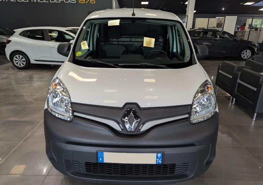 Vue frontale d'un Renault Kangoo Express blanc minéral avec pare-chocs noir mat dans un showroom.