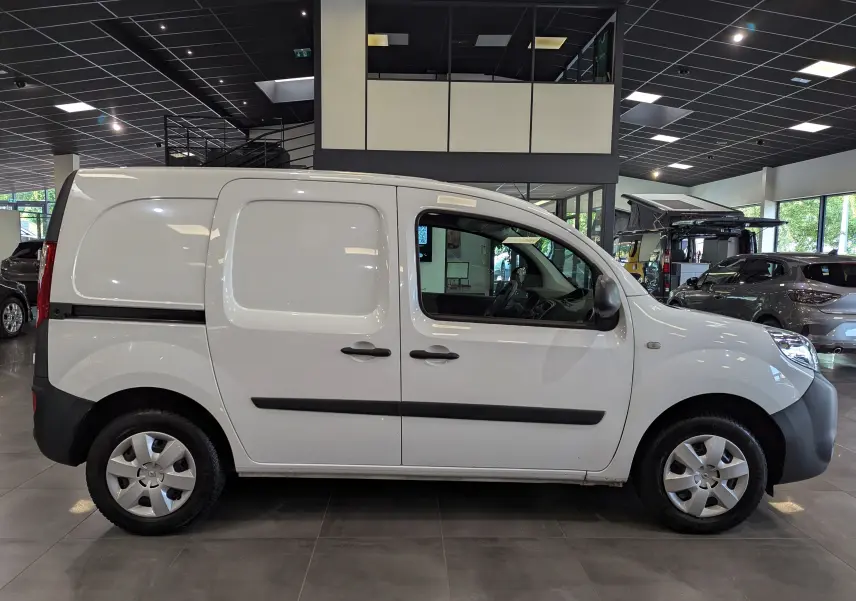 Profil côté droit d'un Renault Kangoo Express blanc minéral, version utilitaire avec portes latérales pleines, en intérieur showroom.