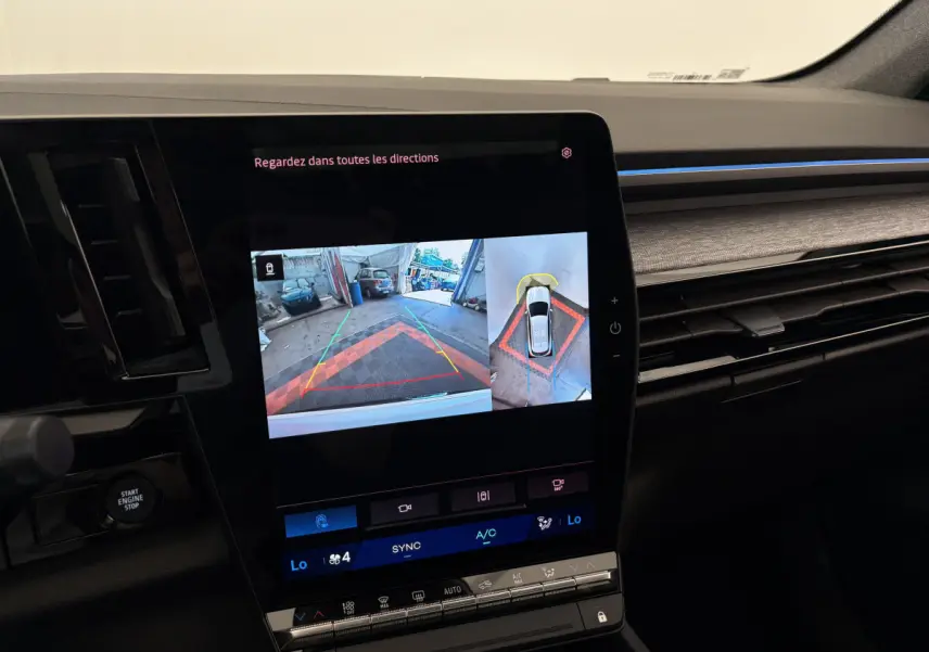 Vue rapprochée de l'écran tactile central du Renault Austral 2025 affichant la caméra de recul et l'aide au stationnement.