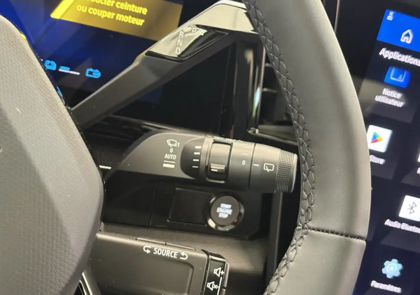 Gros plan sur le volant cuir et la commande de boîte auto du Renault Austral blanc, avec écran tactile et bouton start visible.