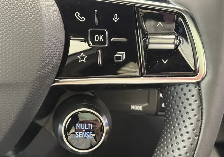 Gros plan sur le volant cuir noir du Renault Austral 2025 avec commandes multifonctions et bouton Multi-Sense lumineux.