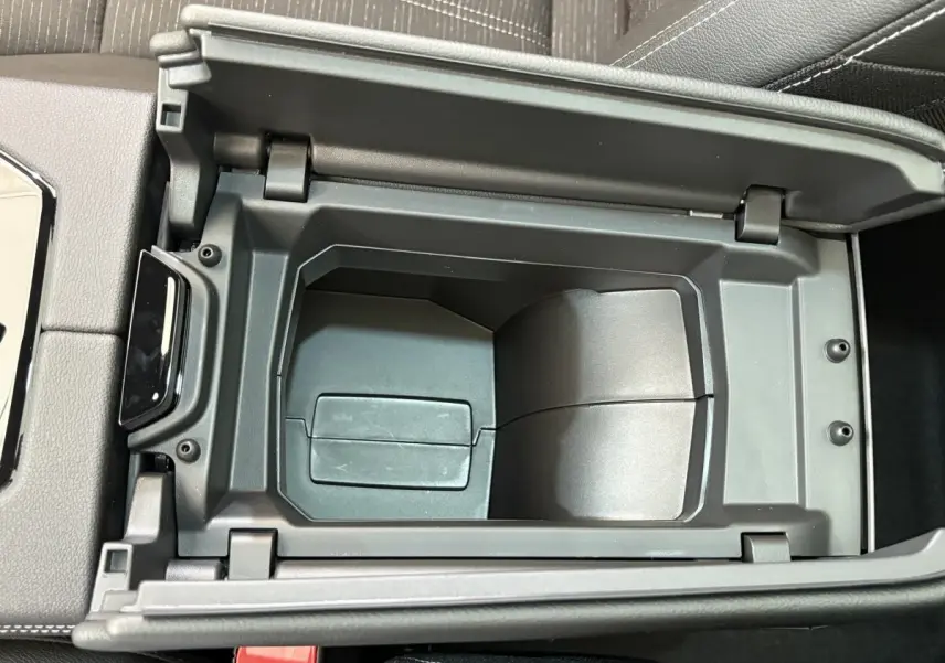 Vue rapprochée de la console centrale ouverte du Renault Austral Techno blanc, montrant le rangement intérieur noir.