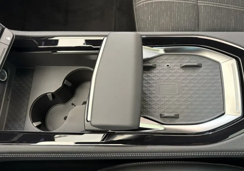 Vue plongeante sur la console centrale noire du Renault Austral 2025 avec accoudoir et emplacement de recharge sans fil.