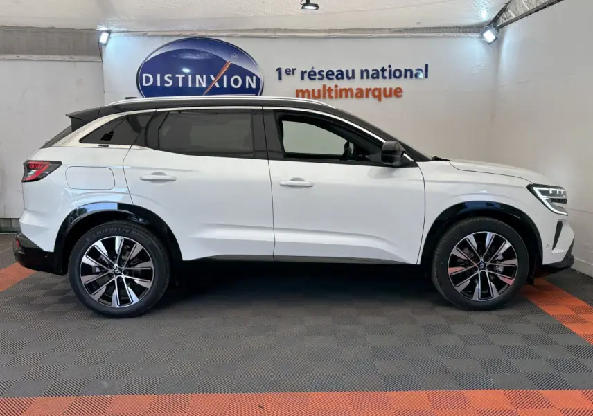 Profil côté gauche du Renault Austral blanc hybride 2025 avec jantes alliage et toit noir contrasté en intérieur showroom.