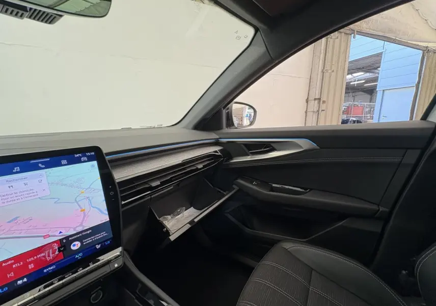 Intérieur côté passager du Renault Austral blanc 2025, tableau de bord moderne avec écran tactile et boîte à gants ouverte.