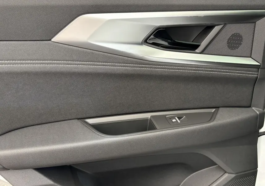 Gros plan sur la porte intérieure côté droit du Renault Austral blanc, avec poignée argentée et bouton de fenêtre.