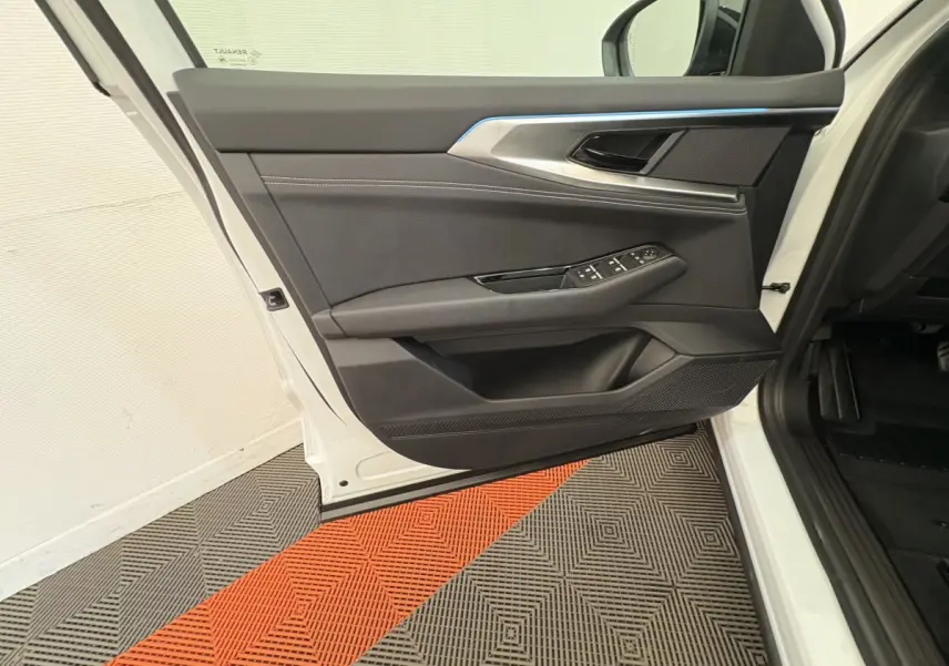 Vue intérieure de la porte avant gauche du Renault Austral blanc 2025 avec garniture noire et commandes électriques.