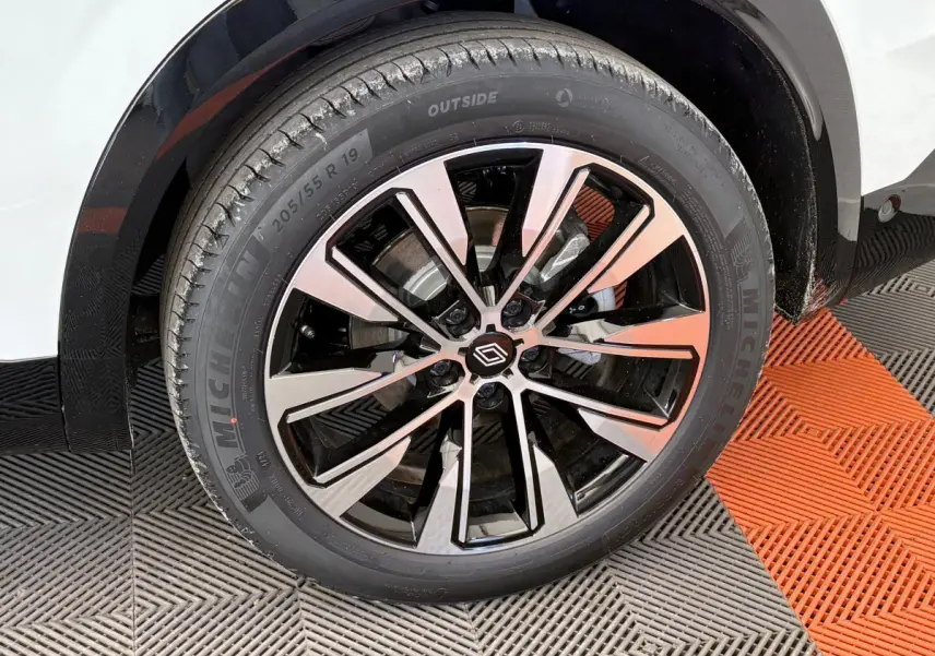 Gros plan sur la roue avant droite du Renault Austral blanc, avec jante alliage noire et argentée au design moderne.