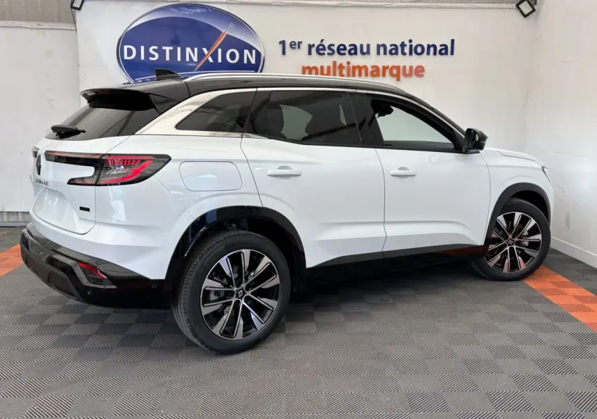 Vue latérale droite d'un Renault Austral blanc 2025 avec toit noir et jantes alliage modernes dans un showroom.