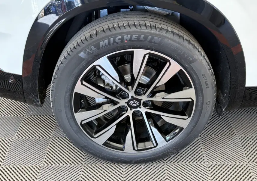 Gros plan sur la roue avant droite du Renault Austral blanc, jante alliage noire et argent avec pneu Michelin.