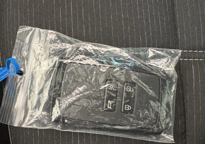 Télécommande noire Renault Austral Techno hybride dans un sachet plastique sur tissu gris à coutures blanches.