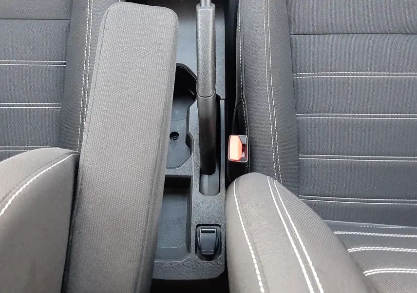 Vue plongeante sur l'accoudoir central et les sièges en tissu noir avec surpiqûres blanches du Dacia Jogger 2025.