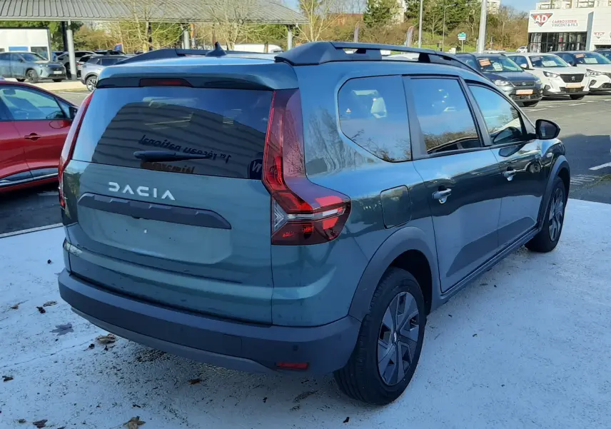 Vue 3/4 arrière droite d'un Dacia Jogger vert cèdre métal 2025 avec toit noir et vitres teintées.