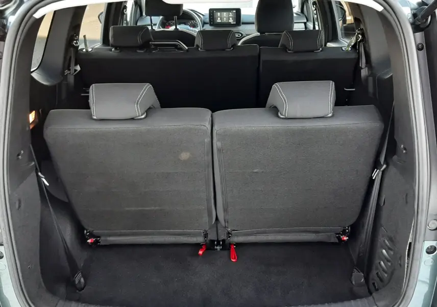 Vue arrière du coffre ouvert d'un Dacia Jogger vert cèdre métal 2025, montrant les sièges arrière rabattus et l'intérieur noir.