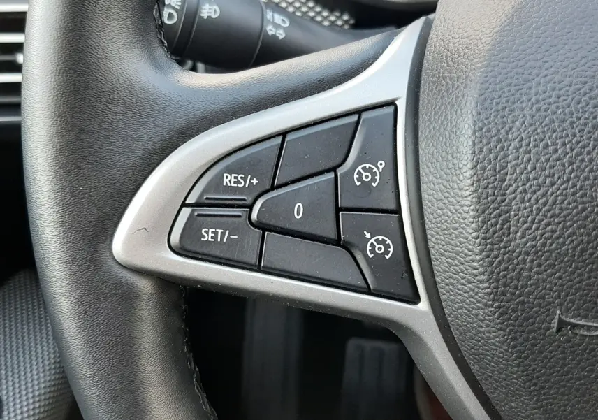 Gros plan sur les commandes de régulateur de vitesse à gauche du volant noir du Dacia Jogger 2025.