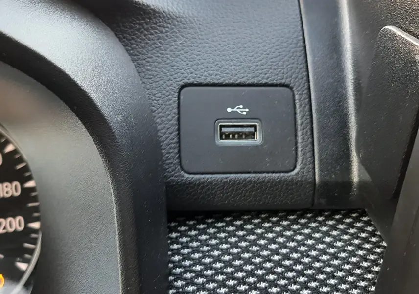 Vue rapprochée du port USB intégré sur la console noire texturée du tableau de bord du Dacia Jogger 2025.