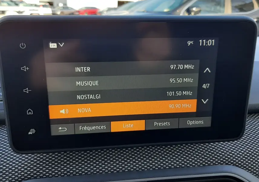 Écran tactile central du tableau de bord du Dacia Jogger affichant la liste des stations radio, avec commandes tactiles et aérateurs en dessous.