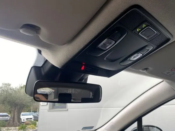 Vue intérieure du plafonnier et du rétroviseur intérieur d’une Renault Clio V gris platine, avec commandes d’éclairage et alerte ceinture.