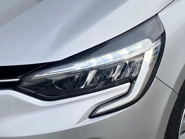 Gros plan sur le phare avant droit de la Renault Clio V TCE 90 Zen gris platine, mettant en valeur son design LED distinctif.
