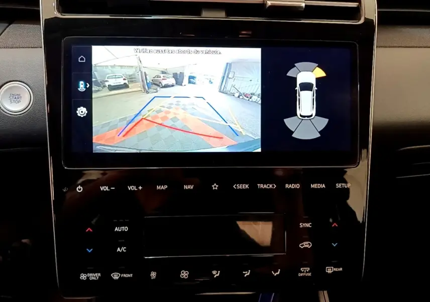Vue rapprochée de l’écran tactile central du Hyundai Tucson gris foncé 1.6 Hybrid 230 Creative avec affichage caméra de recul et radar.
