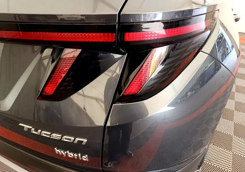 Vue rapprochée arrière droite du Hyundai Tucson gris foncé avec feux LED et logo hybride visible.