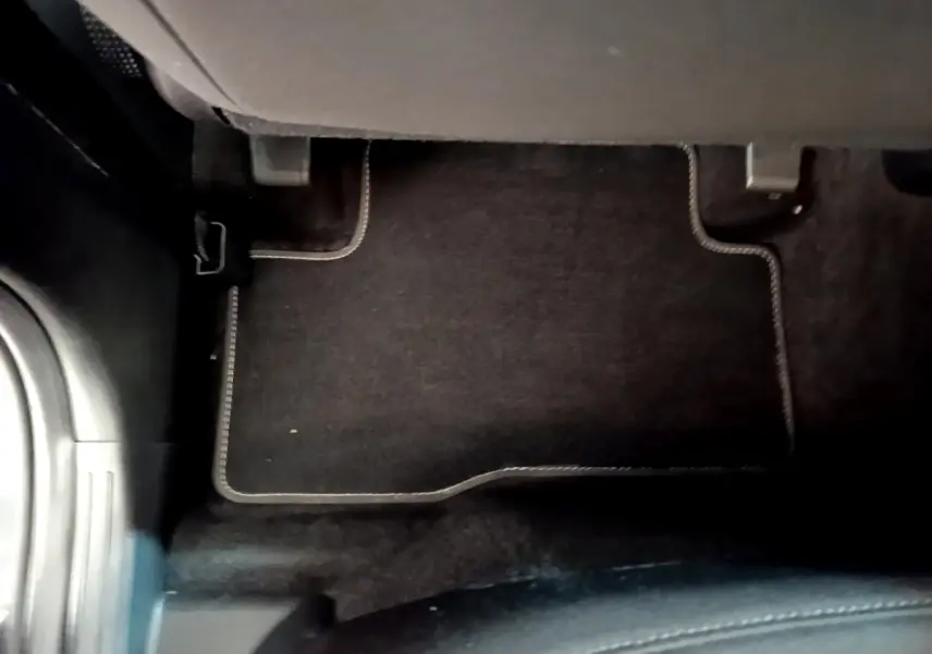 Vue rapprochée du tapis de sol noir avec surpiqûres blanches côté passager arrière d’un Hyundai Tucson gris foncé.