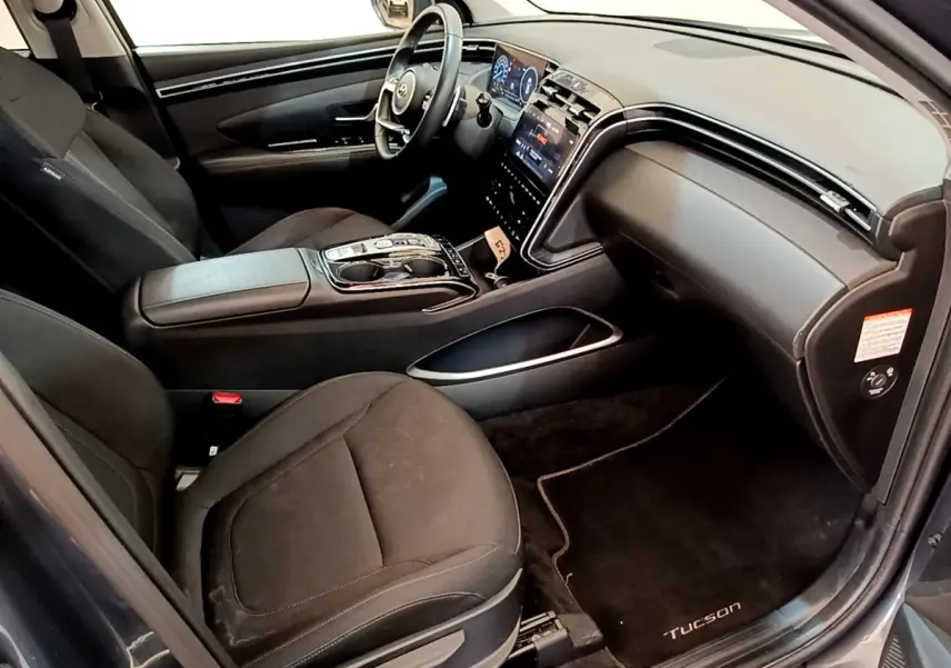 Vue intérieure côté passager du Hyundai Tucson 1.6 Hybrid 230 Creative 2022 avec sièges noirs et tableau de bord moderne.