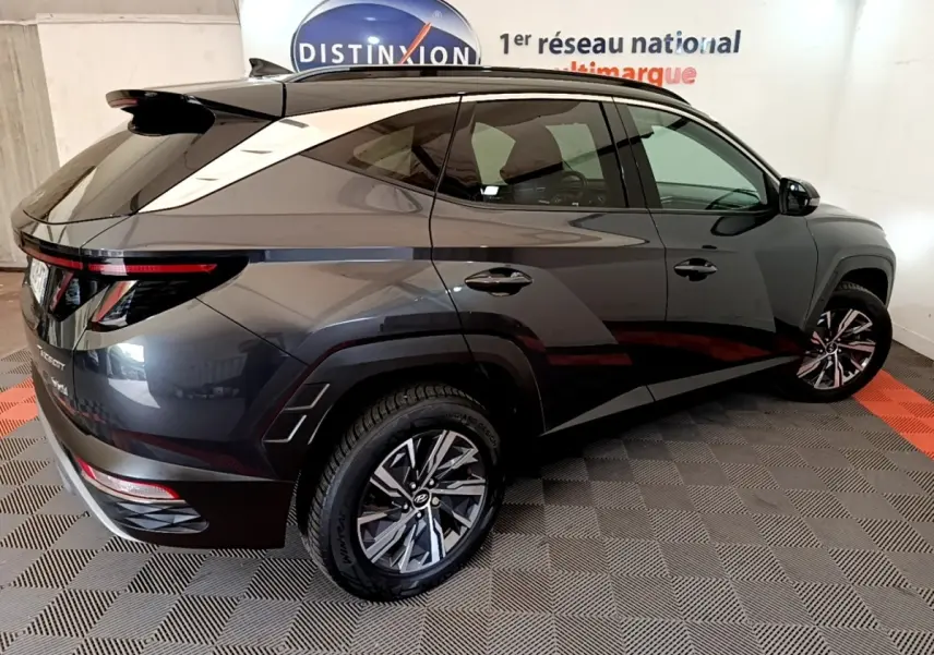 Vue 3/4 arrière droite d’un Hyundai Tucson gris foncé 2022 avec jantes alliage et toit noir contrasté.