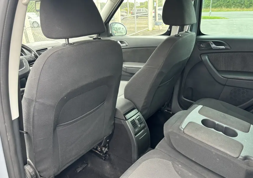 Vue intérieure arrière du Skoda Yeti gris 2012, montrant les sièges avant en tissu noir et l'accoudoir central arrière avec porte-gobelets.