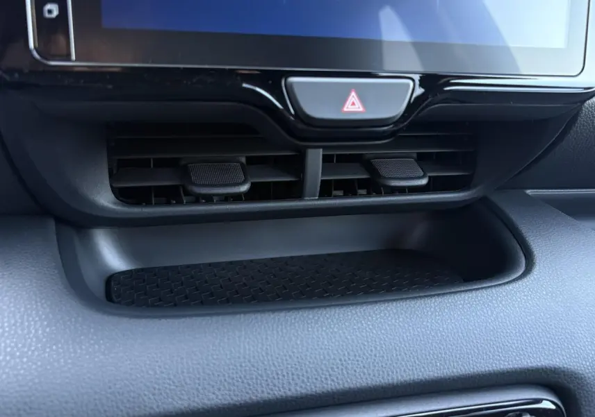 Détail de la console centrale noire de la Toyota Yaris hybride 2025 avec écran tactile et commandes d'aération visibles.