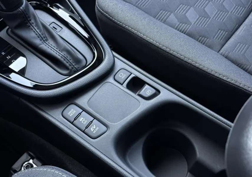 Gros plan sur la console centrale de la Toyota Yaris Hybride 2025, montrant levier de vitesses et commandes de modes de conduite.