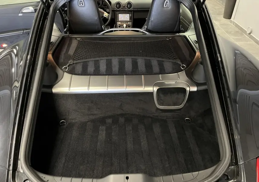 Vue arrière du coffre noir du Porsche Cayman 987 avec filet de rangement et intérieur cuir visible au loin