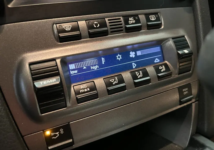 Détail de la console centrale du Porsche Cayman 987 noir, affichage digital de la climatisation et boutons de réglage.