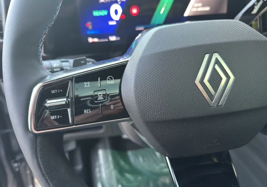 Gros plan sur le volant cuir multifonctions noir de la Renault Austral New 200 Esprit Alpine avec affichage digital en arrière-plan.