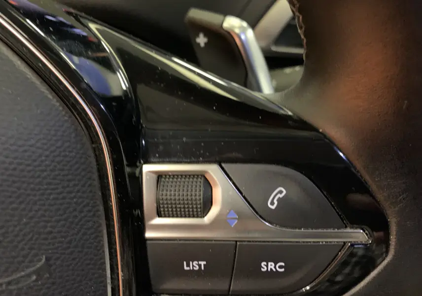 Gros plan sur les commandes de volume et téléphone au volant en cuir noir d'un Peugeot 3008 2020.