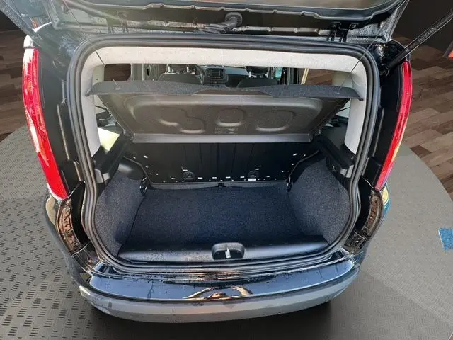 Coffre ouvert vu de l'arrière d'une Fiat Panda noire 2025, montrant l'espace de chargement vide et la tablette cache-bagages.