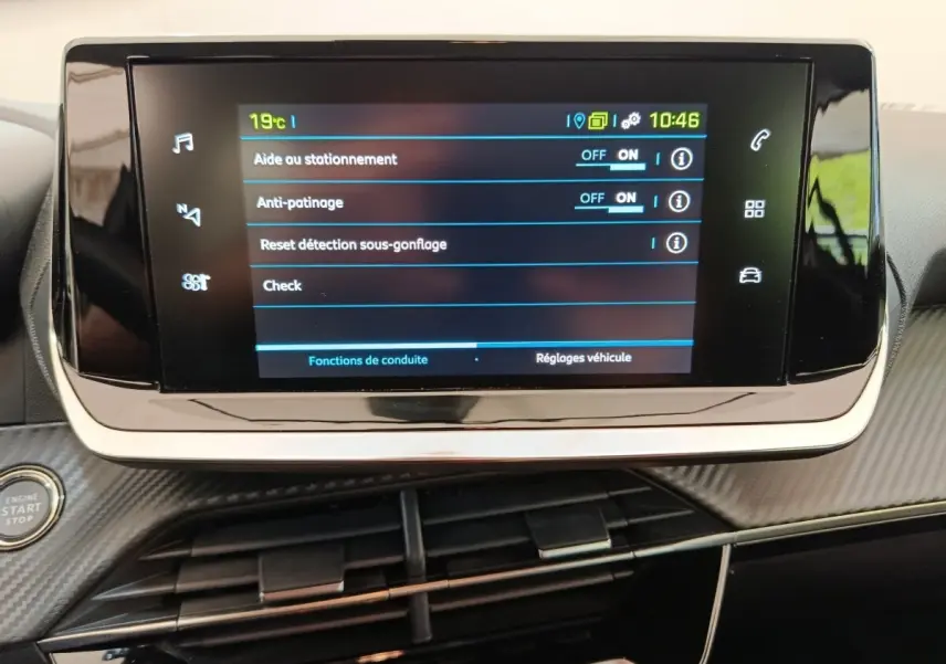 Écran tactile central affichant les réglages d’aide au stationnement et d’anti-patinage dans un Peugeot 208 électrique blanc.